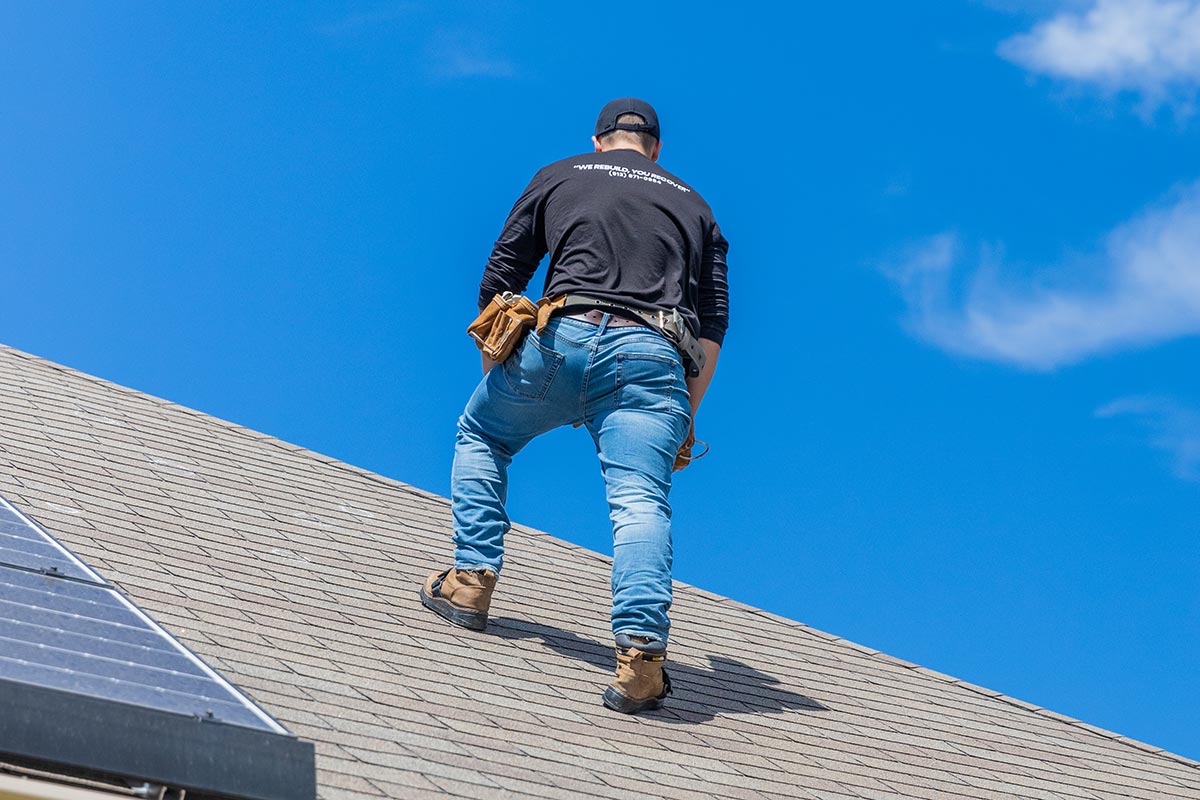 Roof inspector assessing roof with blue sky overhead